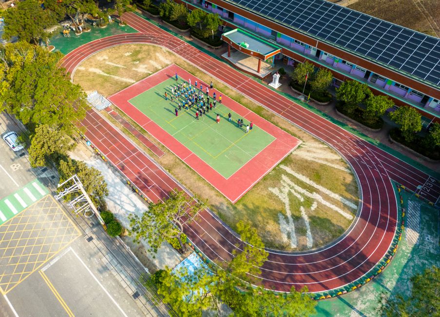 Aerial shot showcasing a school sports area with students on a court, surrounded by a running track.
