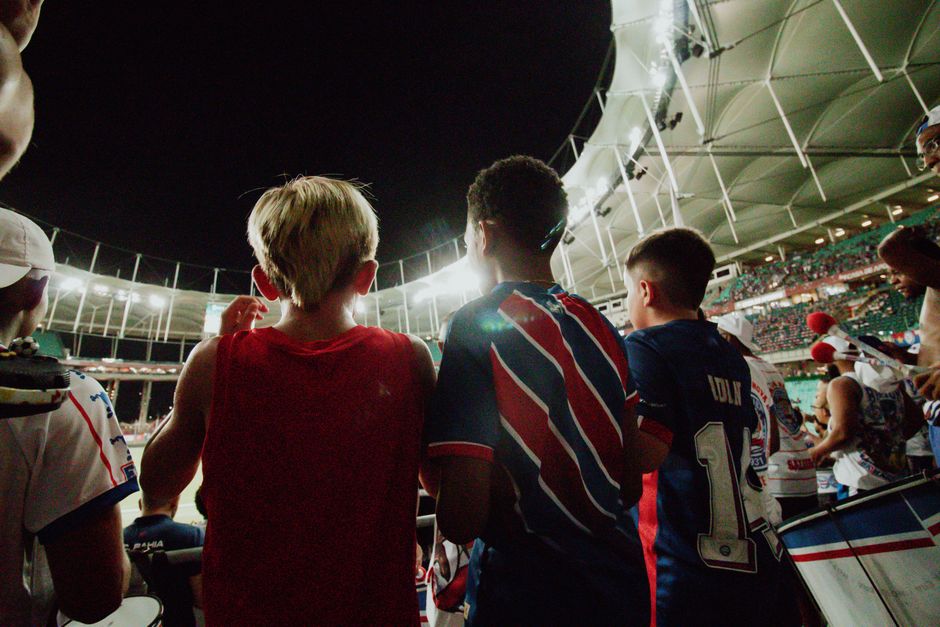 Fans cheer from the stands during a night soccer game in a large stadium, full of energy and excitement.